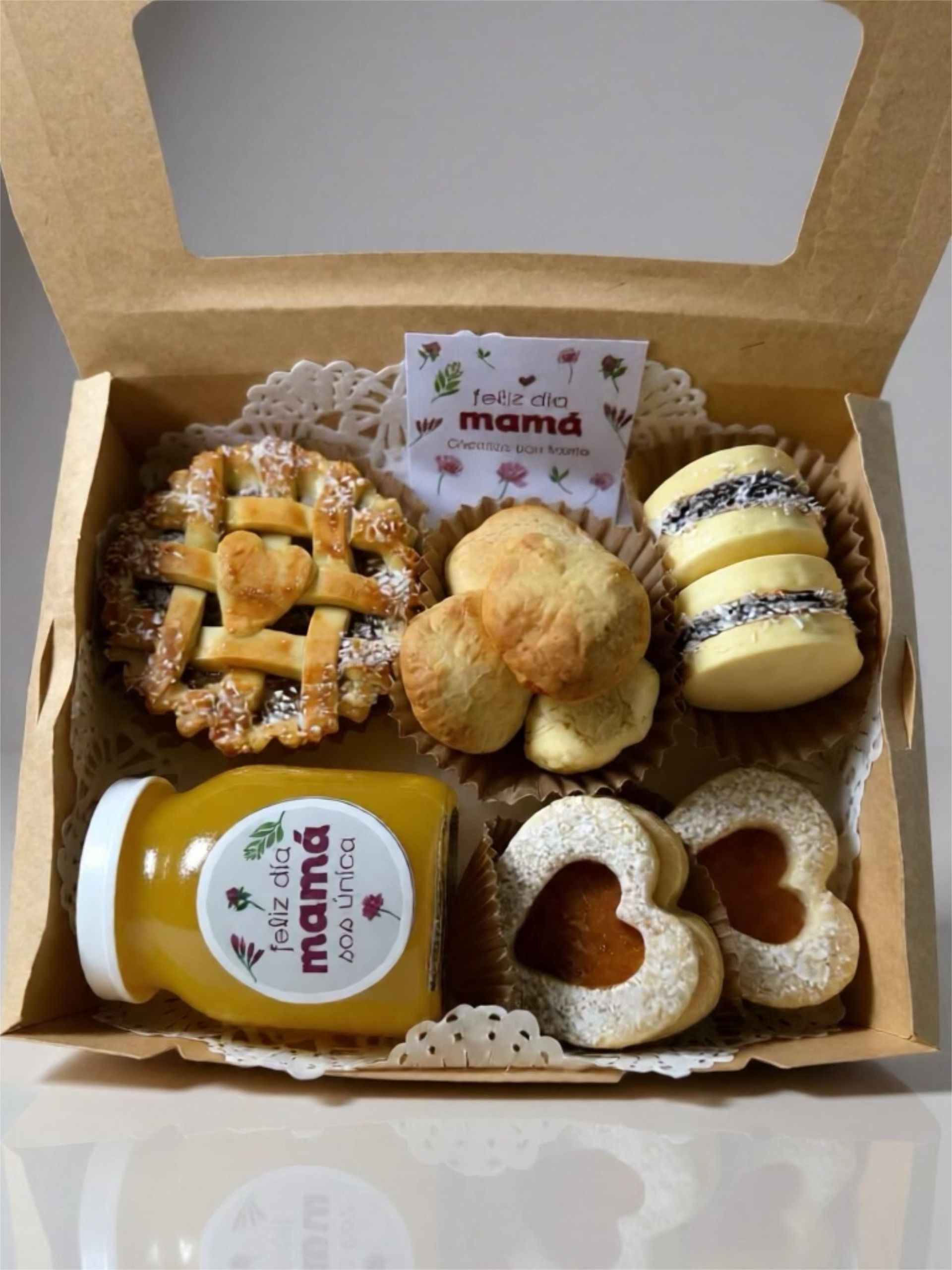 Caja de golosinas que incluye un pastel, galletas y un frasco de jugo con la etiqueta