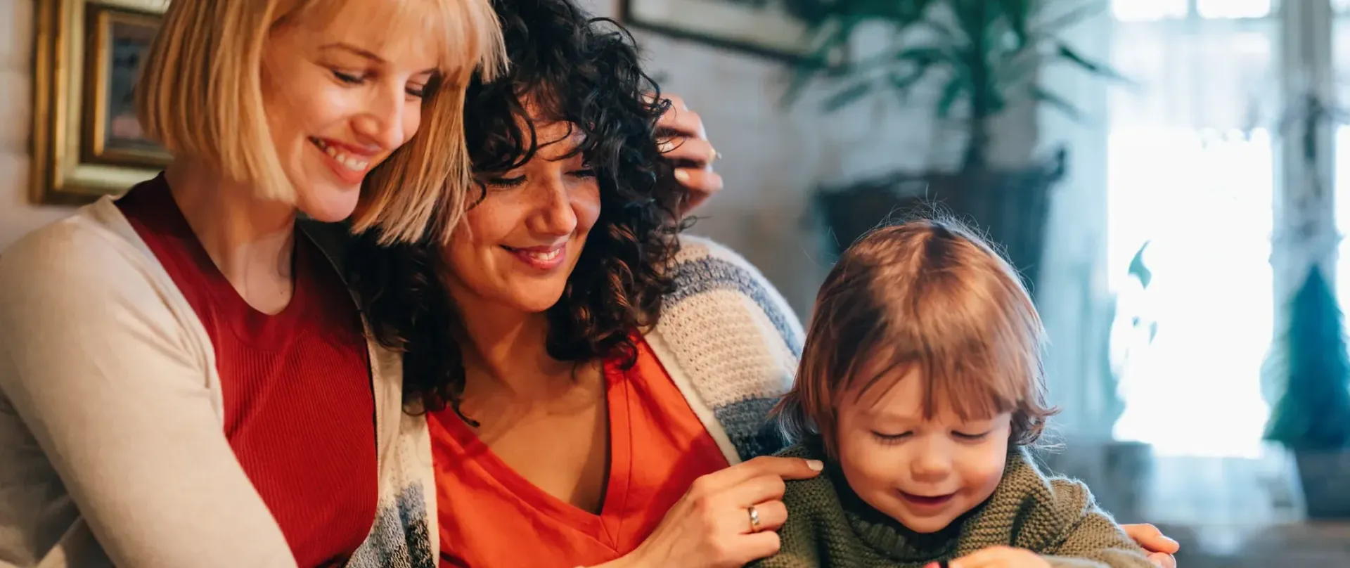 Two women and a child are sitting next to each other in a living room.