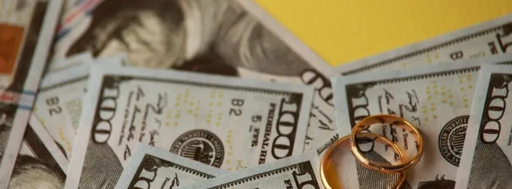 A pair of wedding rings are sitting on top of a pile of money.