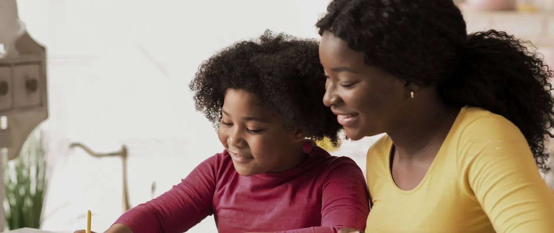 A woman is helping a little girl with her homework.