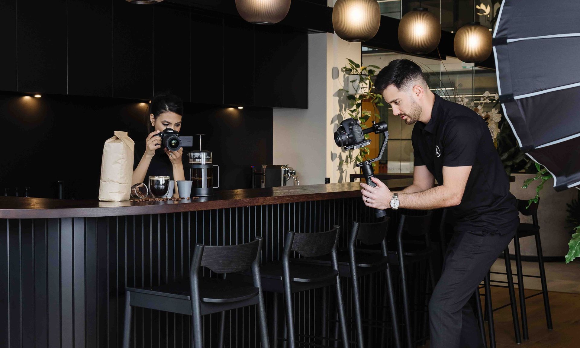 Two people filming coffee setup in a cafe.