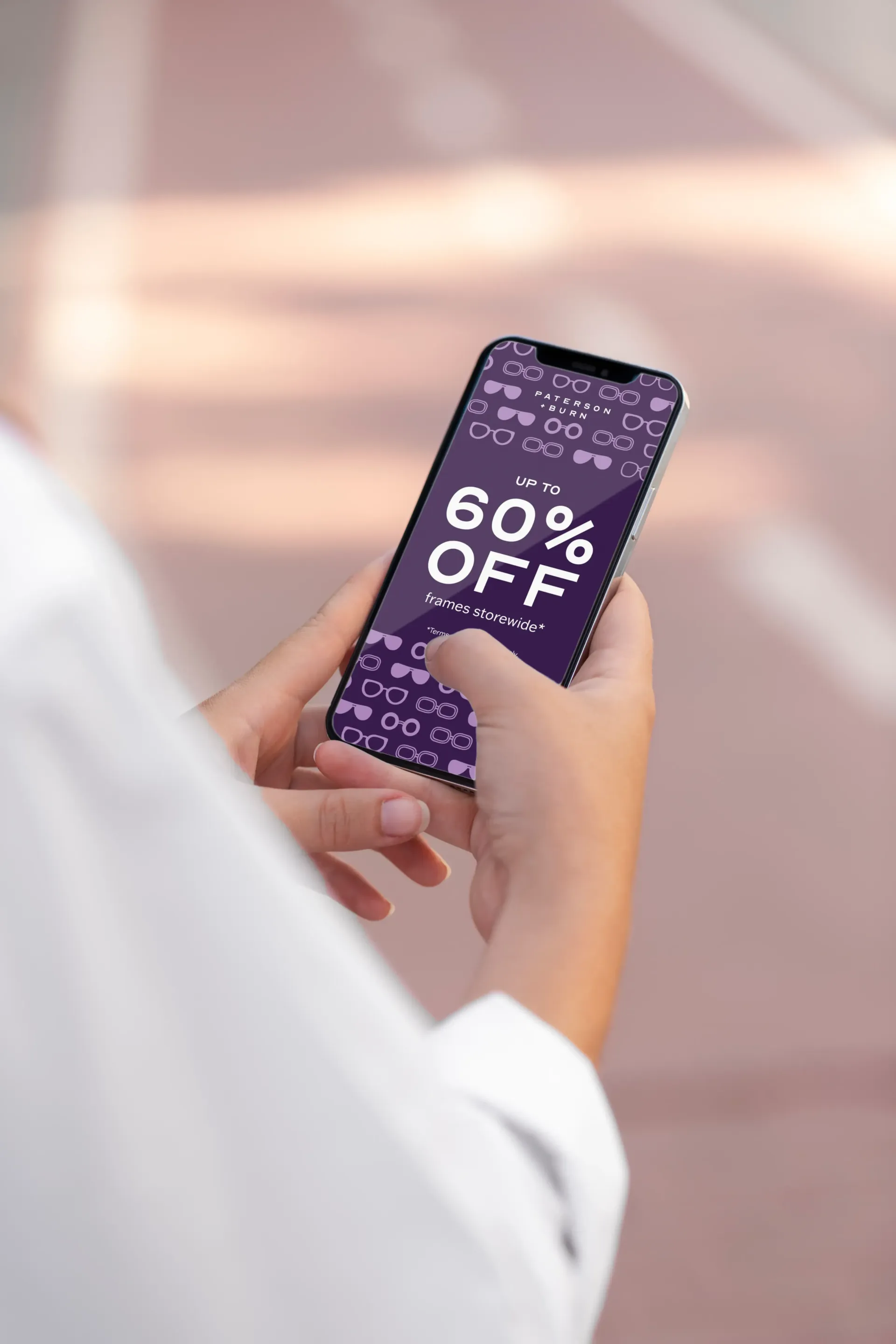 Person holding a phone displaying a purple 60% off sale ad.