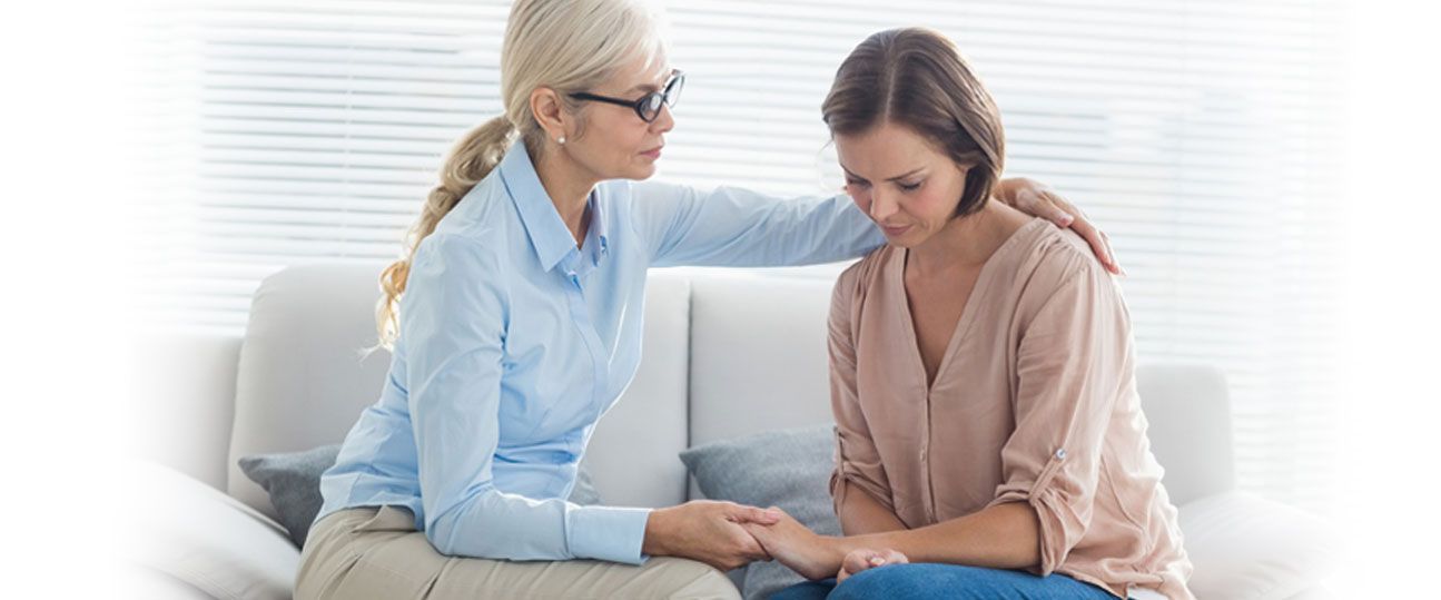 a woman is comforting another woman while sitting on a couch