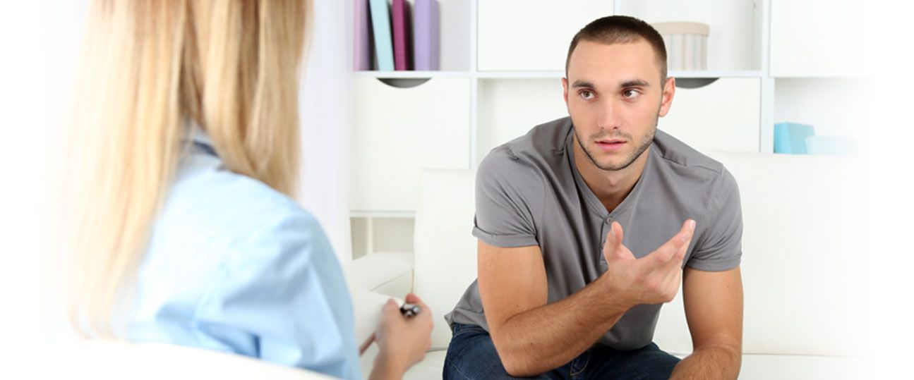 a man is sitting on a couch talking to a woman 