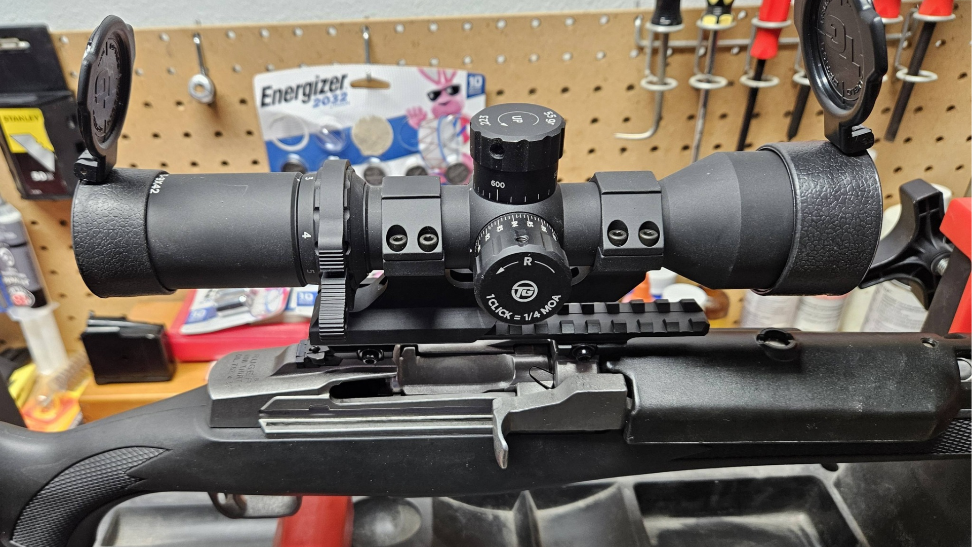 Rifle on workbench with black scope and eyepieces in a workshop setting