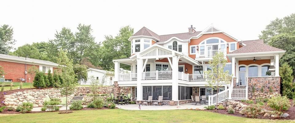 A large house with a lot of windows is sitting on top of a lush green lawn.