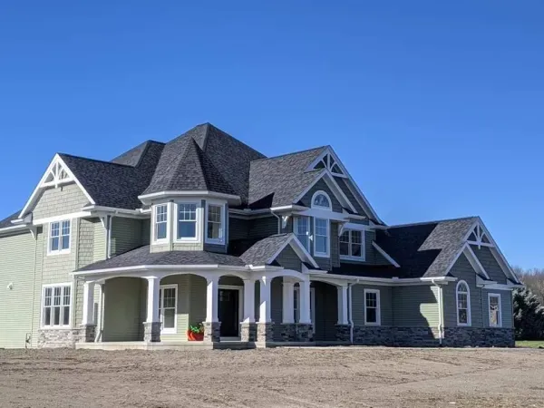 A large house with a porch and a blue sky in the background