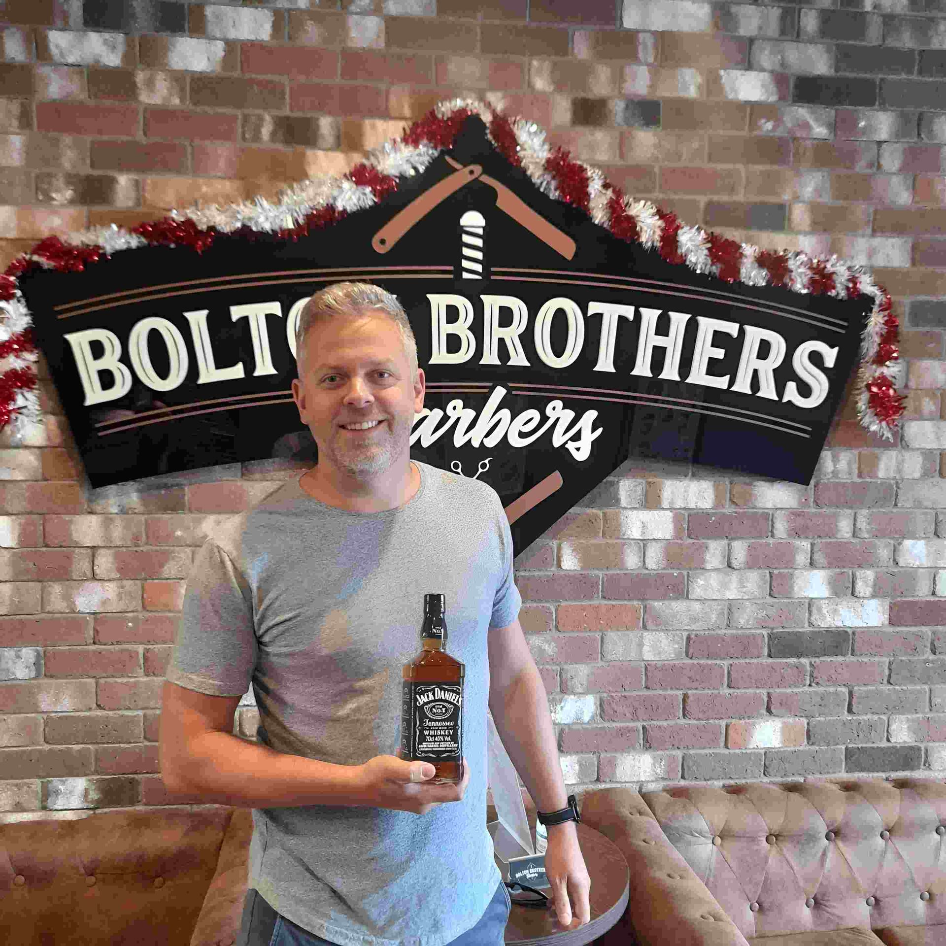 Man Holding Jack Daniel's Bottle In Barbershop — Bolton Brothers Barbers in Erina, NSW
