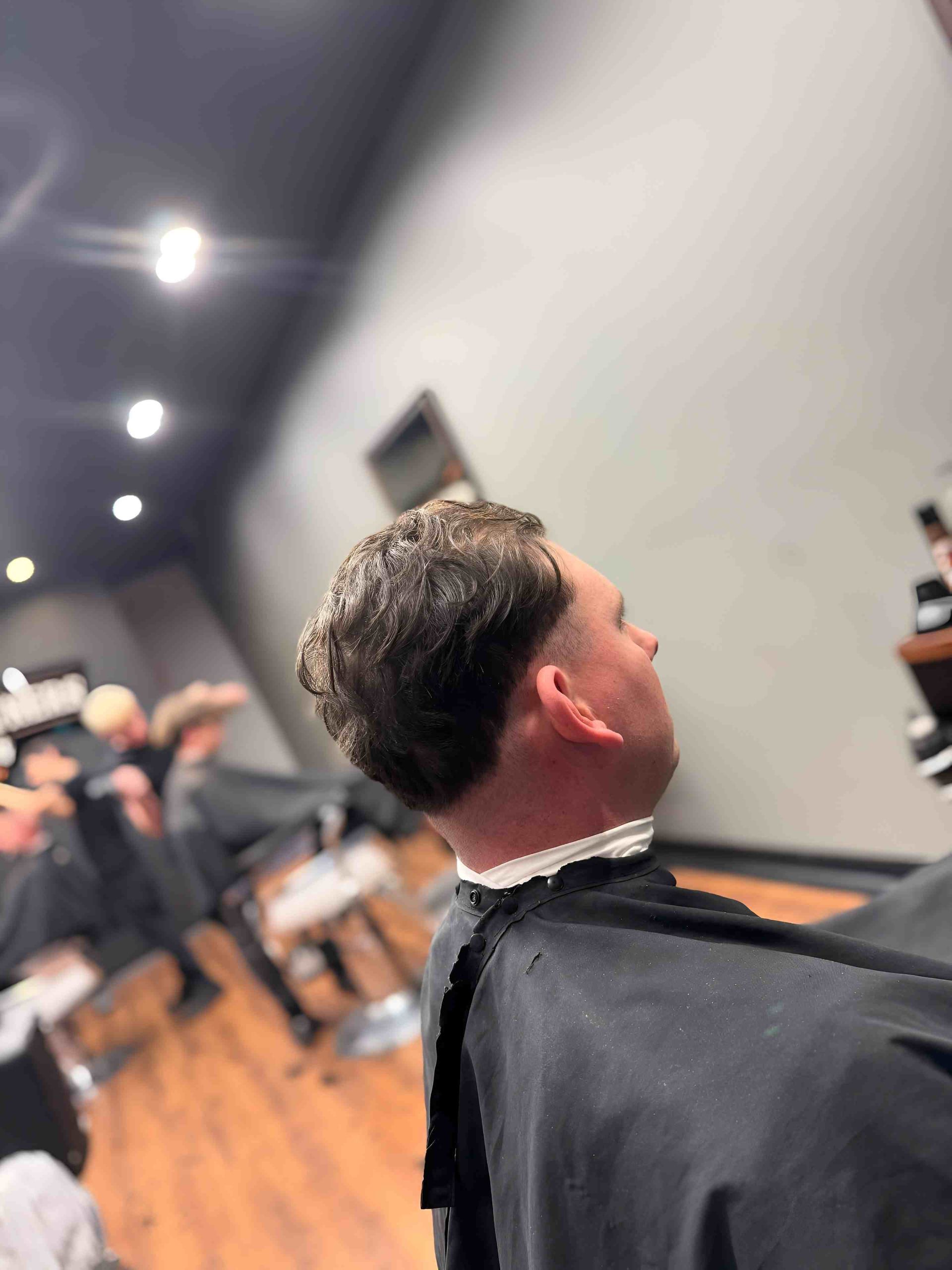 Man With Fresh Haircut Wearing Barber Cape — Bolton Brothers Barbers in Erina, NSW