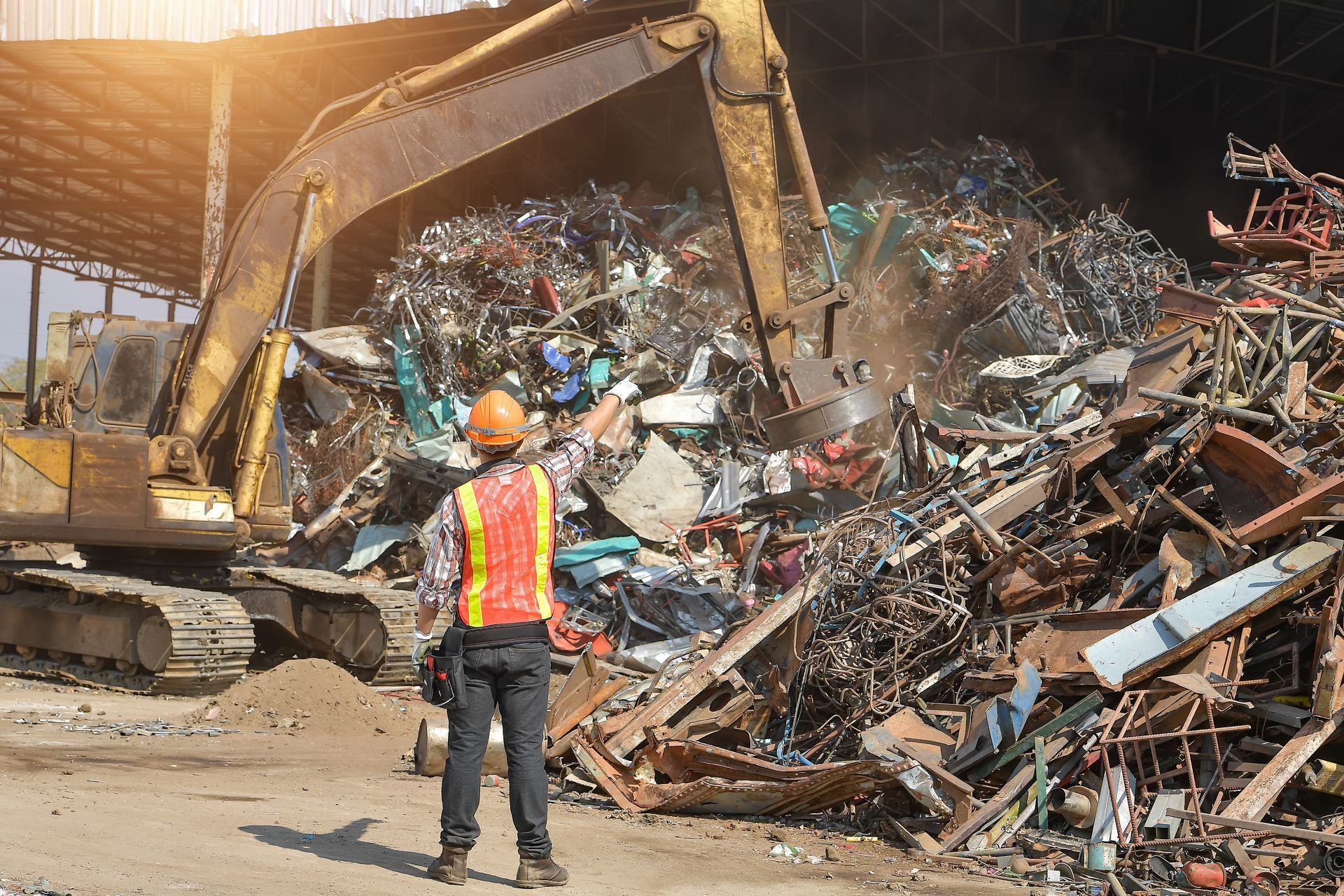 Metal scrap yard pointing at an excavator with a magnet Metal scrap yard pointing at an excavator with a magnet