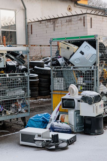 Electronic waste recycling yard with dumpsters, and old appliances showcasing white goods drop-off. Electronic waste recycling yard with dumpsters, and old appliances showcasing white goods drop-off.