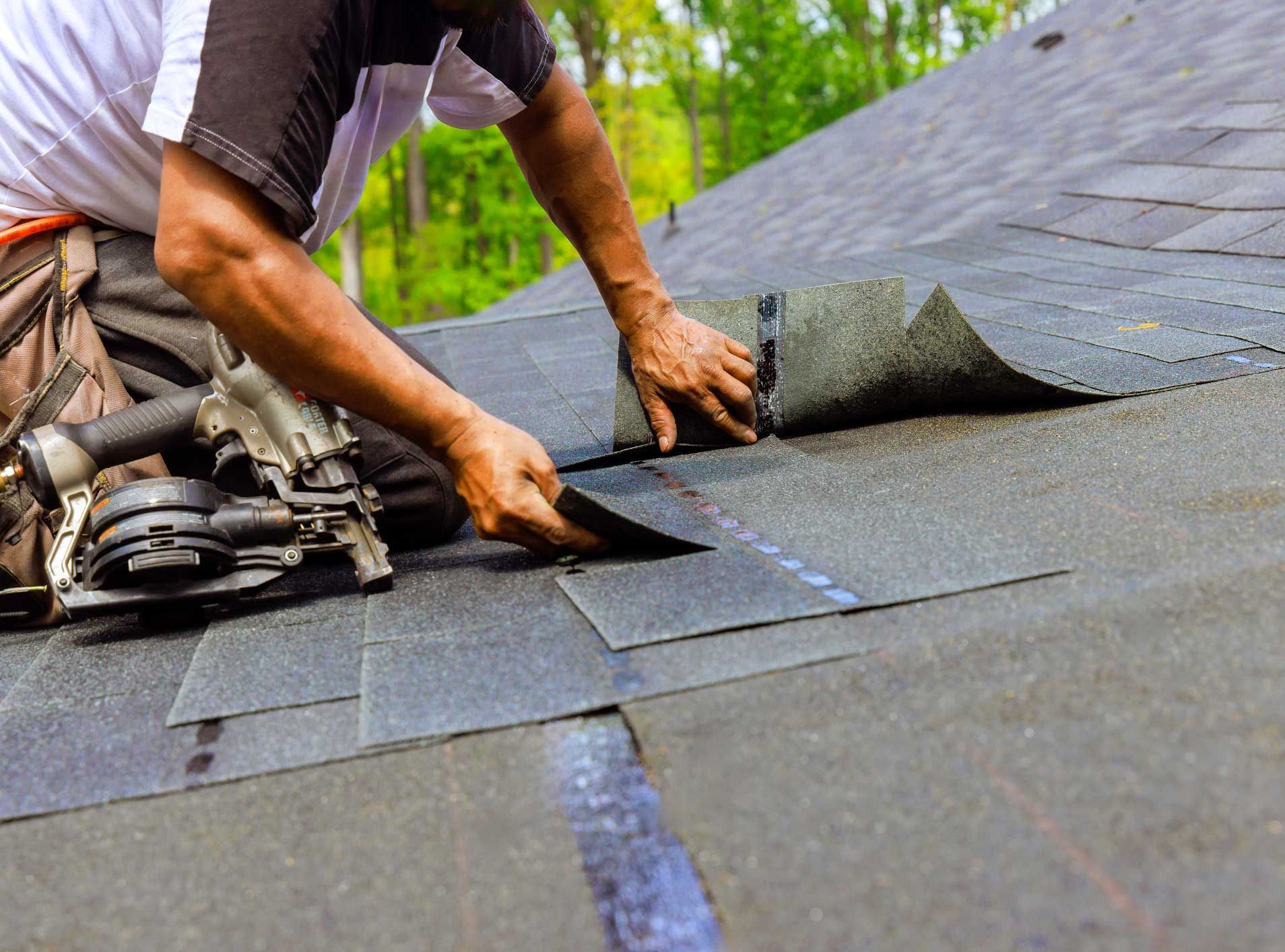 A man is laying shingles on a roof.