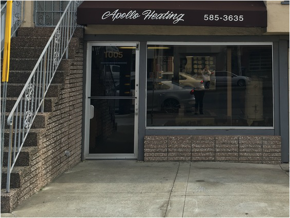 Storefront entrance with large window and sign reading “Apollo Heating,” beside a staircase and sidewalk.