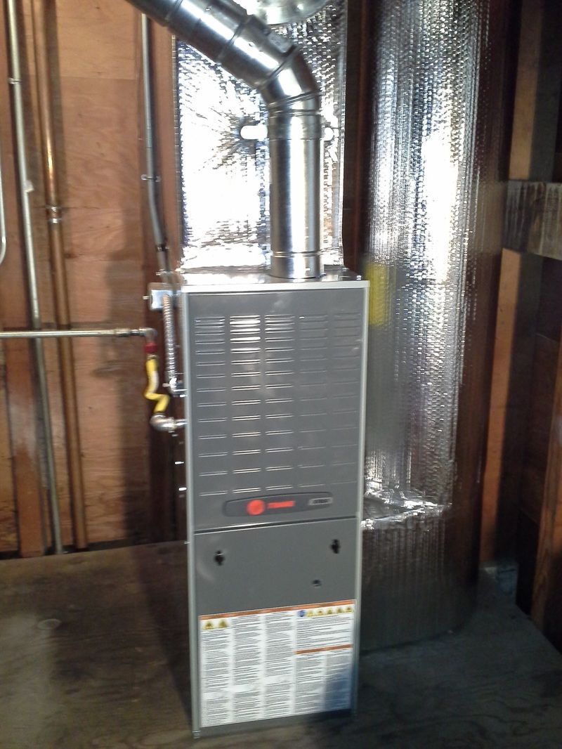 Furnace unit in unfinished basement with exposed ducts and insulation