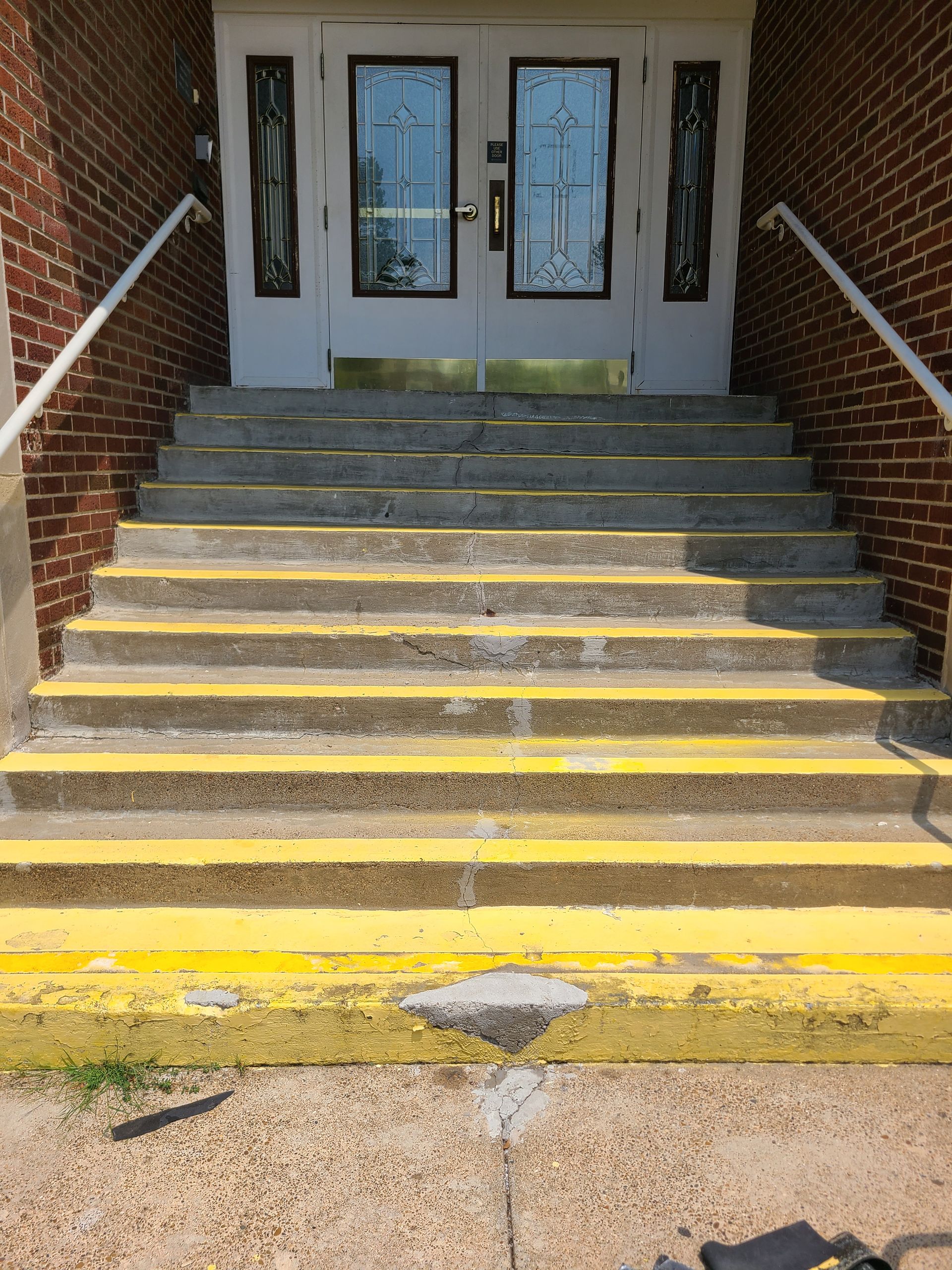 A concrete porch in front of a brick building with a wooden door.
