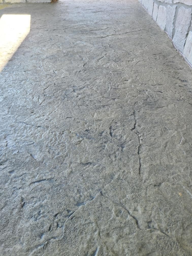 A close up of a concrete walkway with a brick wall in the background.