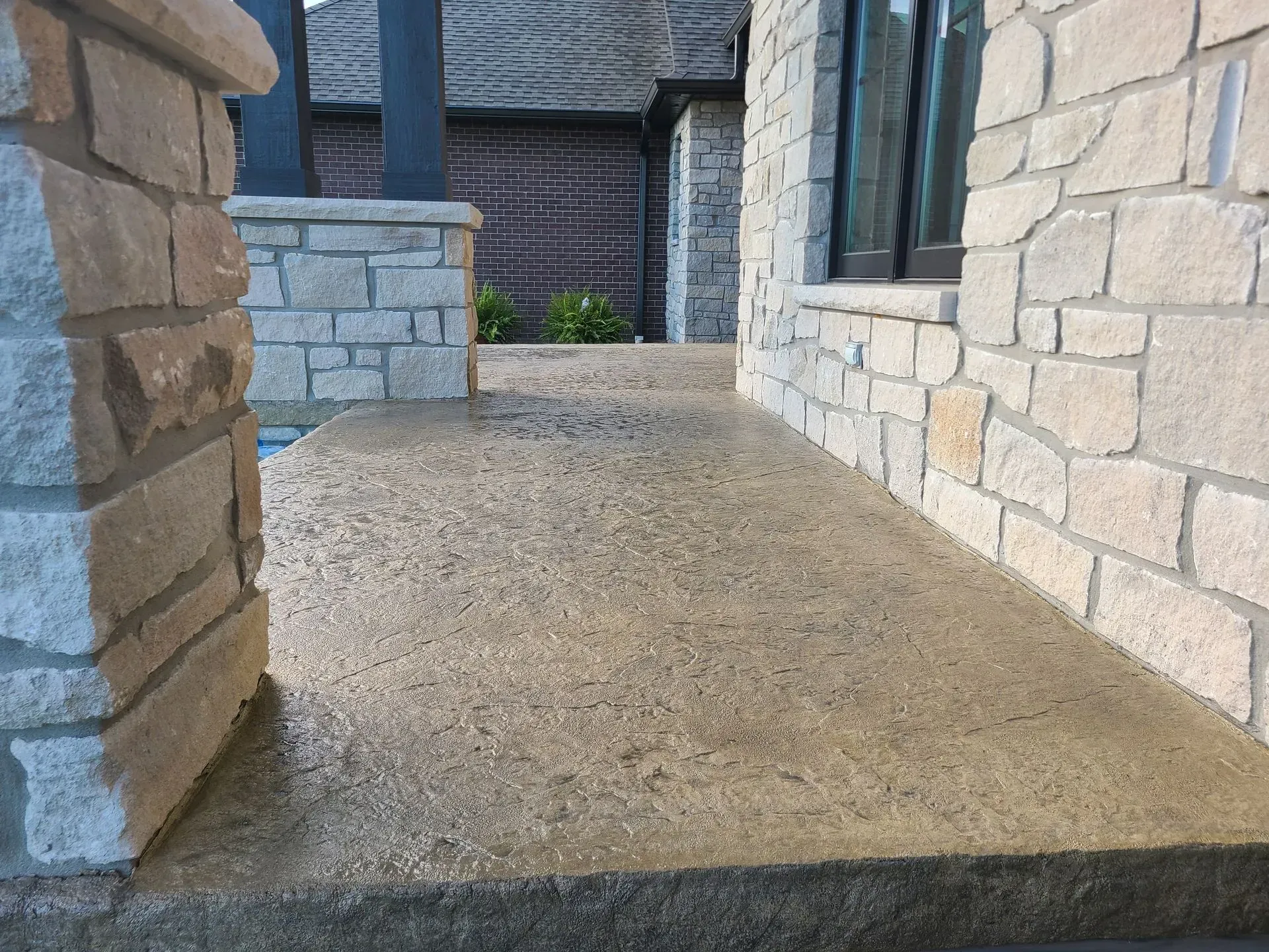 A stone wall with a concrete walkway in front of it.