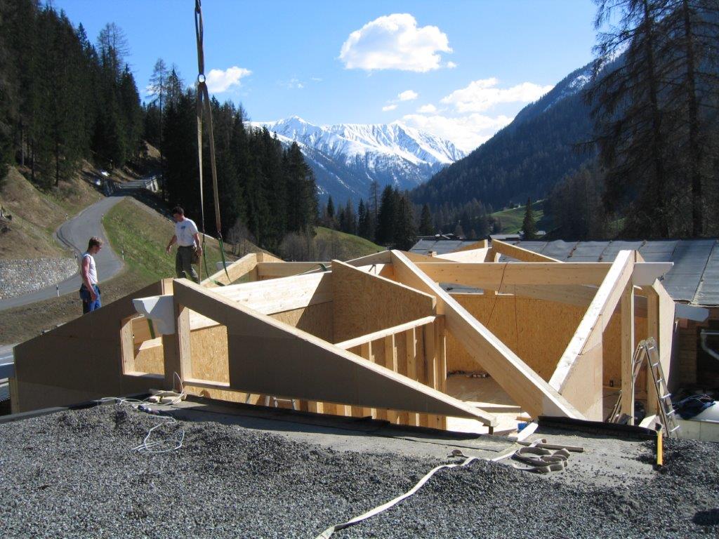 Eine große Holzkonstruktion wird mit Bergen im Hintergrund gebaut