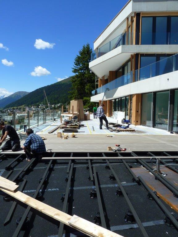 Eine Gruppe von Männern arbeitet auf einem Deck vor einem Gebäude