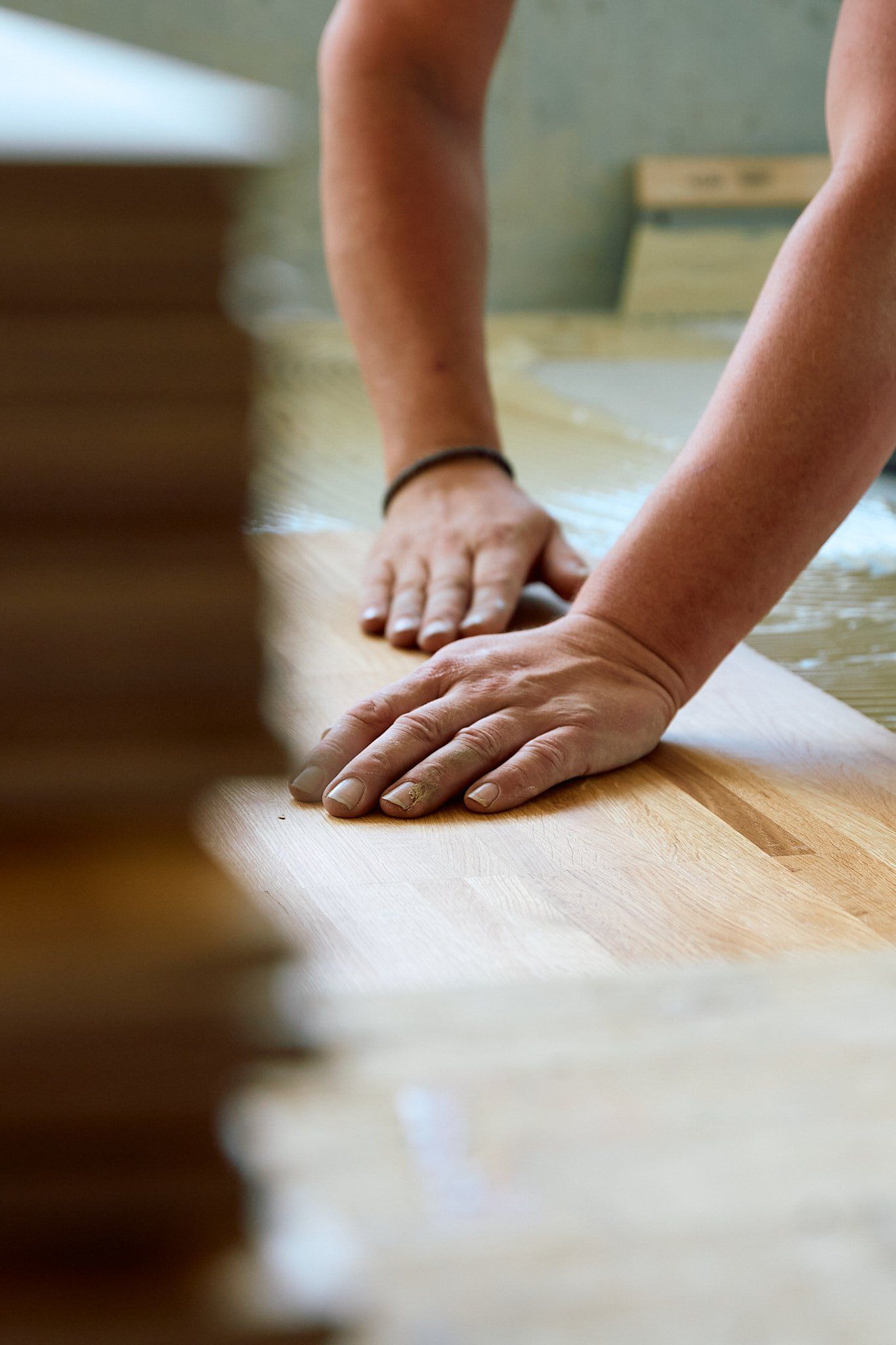 Eine Person verlegt Holzdielen auf einem Holzboden.