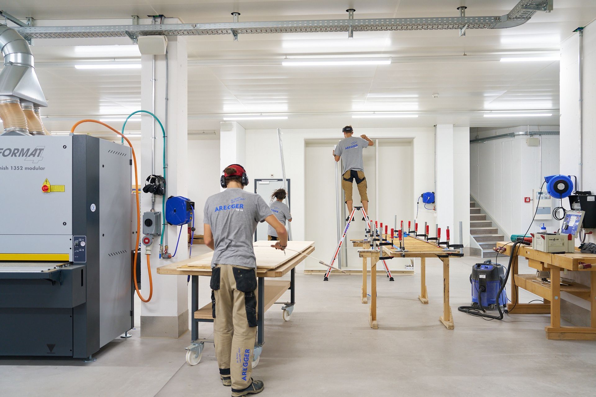 Eine Gruppe von Menschen arbeitet in einem großen Raum in einer Fabrik.