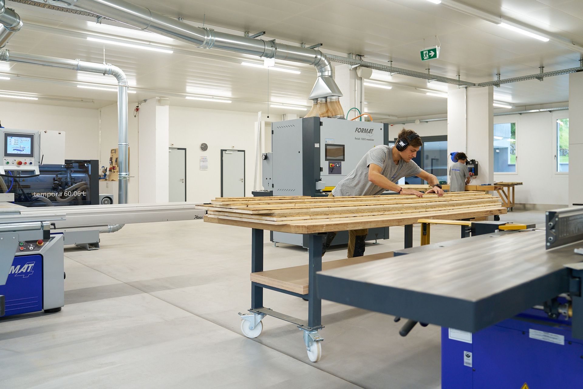 Ein Mann bearbeitet in einer Fabrik ein Stück Holz.
