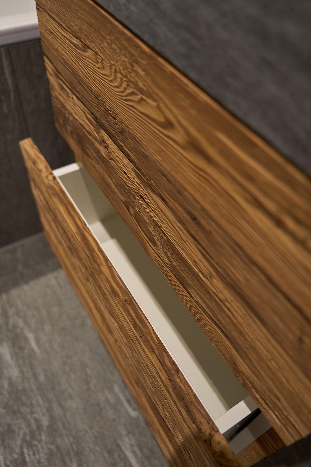 Ein Holzschrank mit einer offenen Schublade in einem Badezimmer.