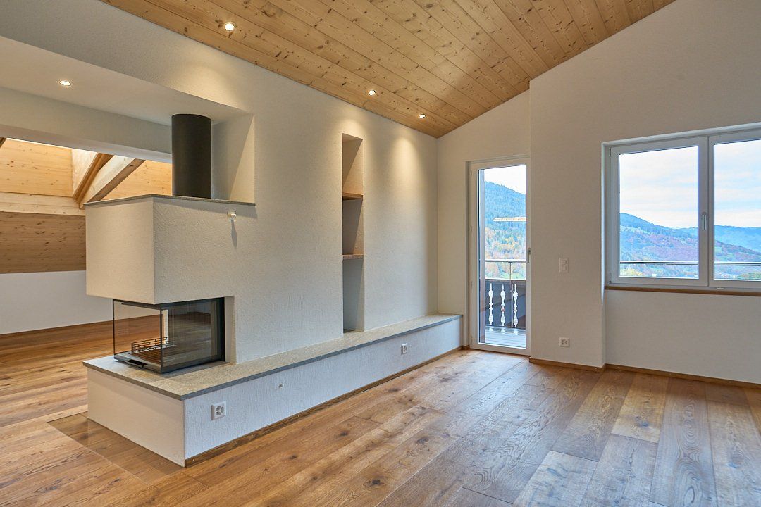 Ein leeres Wohnzimmer mit Hartholzböden und einem Kamin