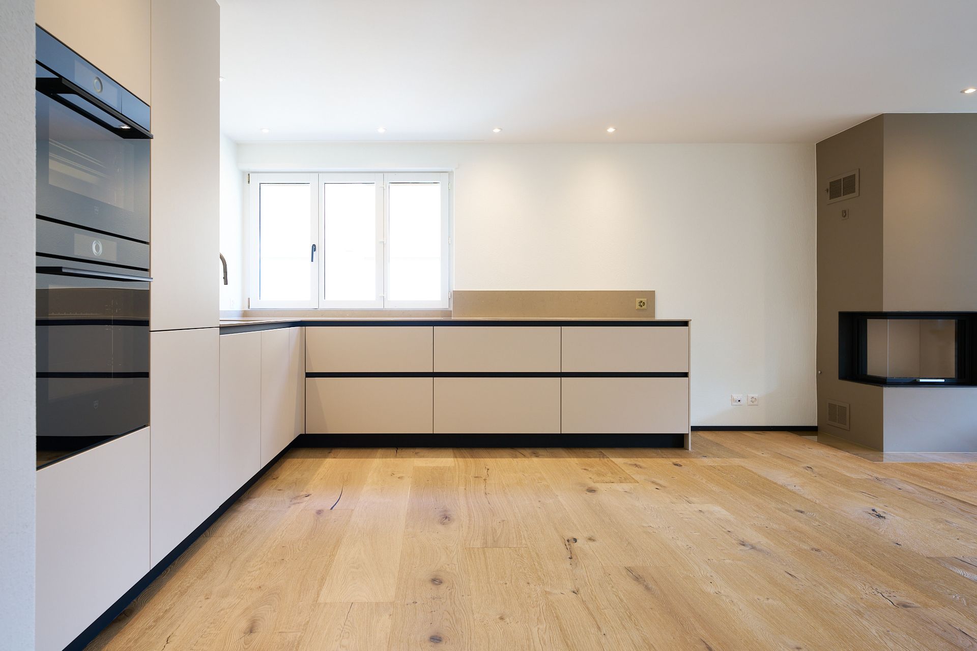 Eine leere Küche mit Holzböden und weißen Schränken