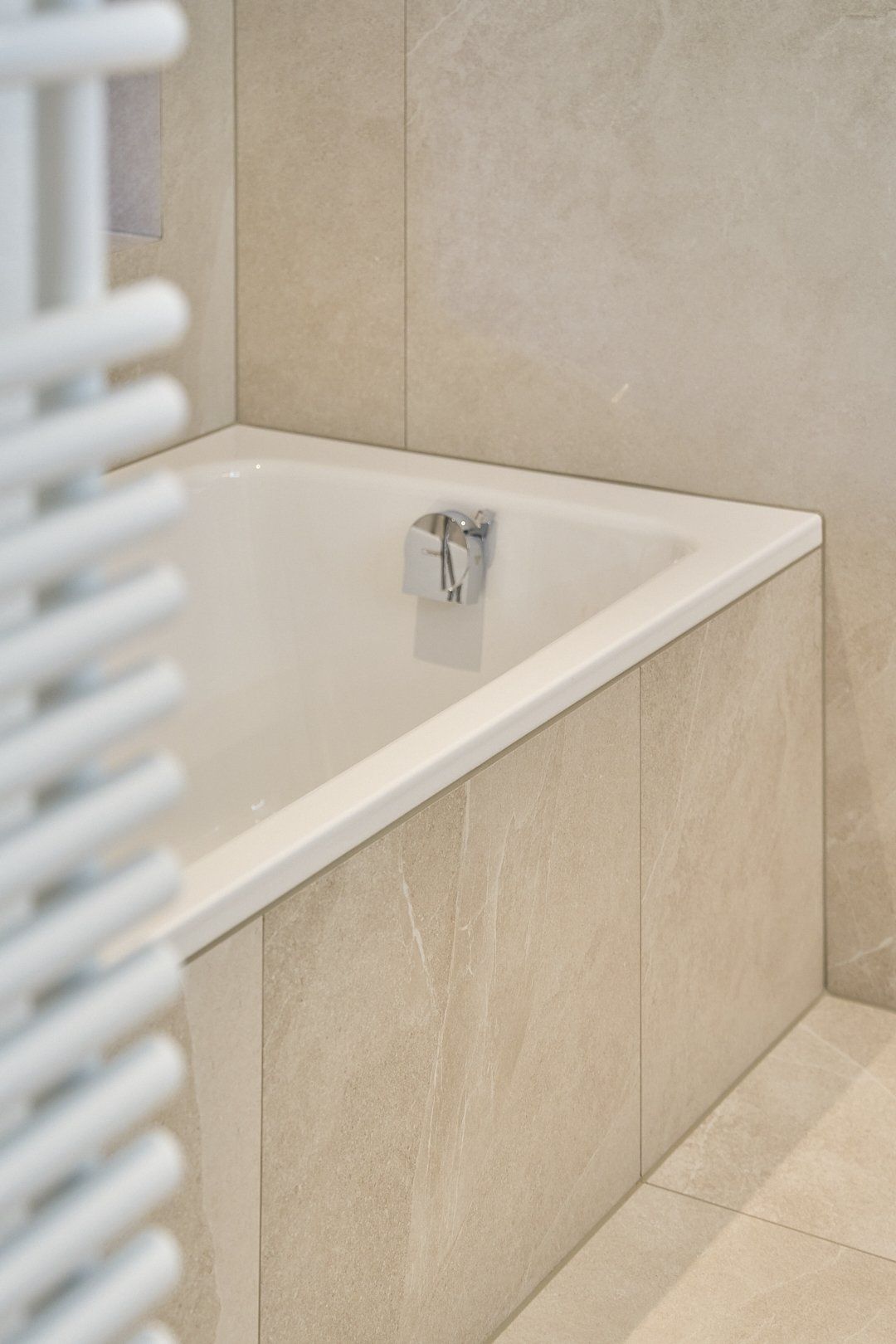 Eine Badewanne in einem Badezimmer neben einem Handtuchhalter.