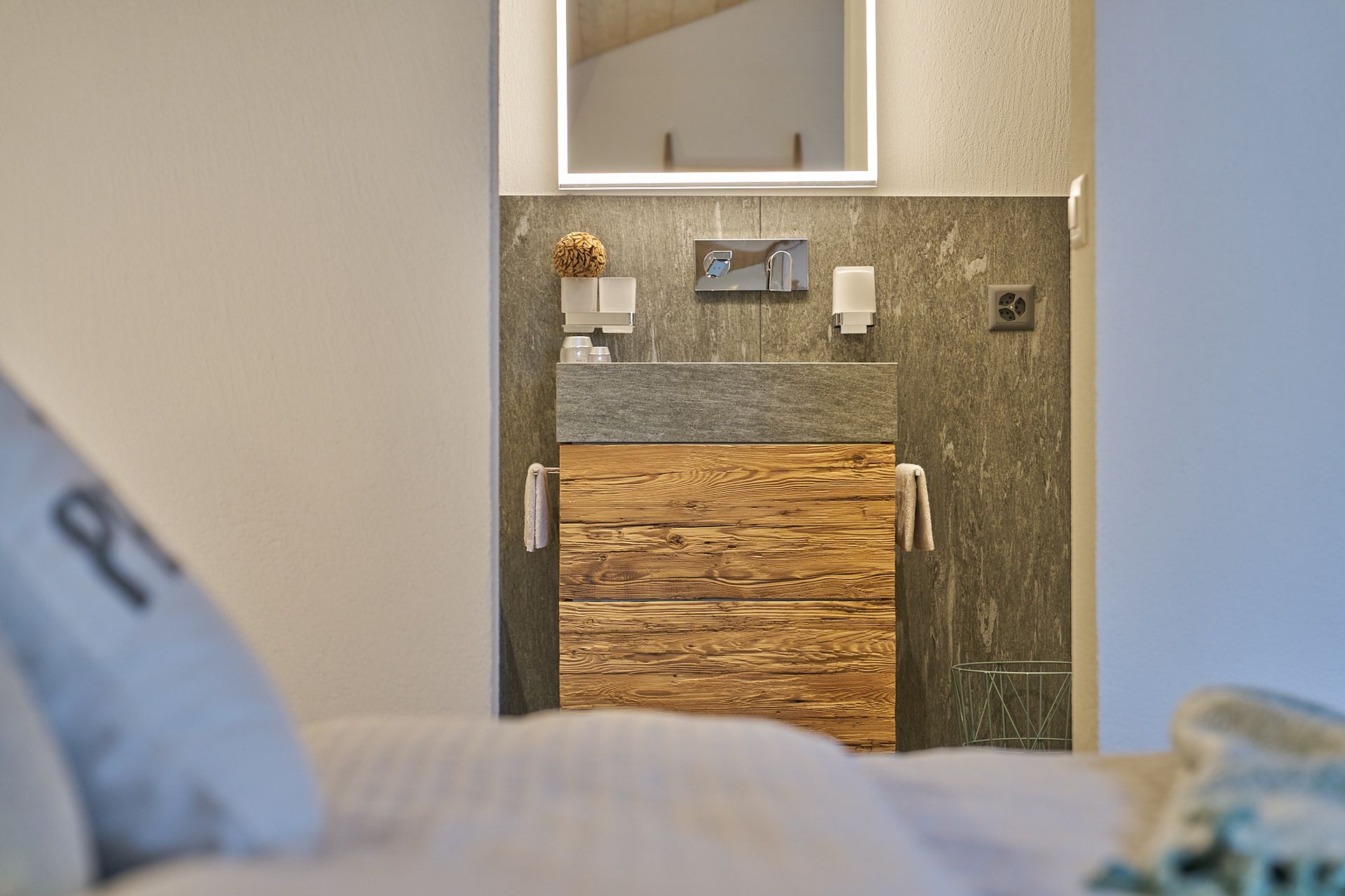 Ein Badezimmer mit Waschbecken und Spiegel neben einem Bett.