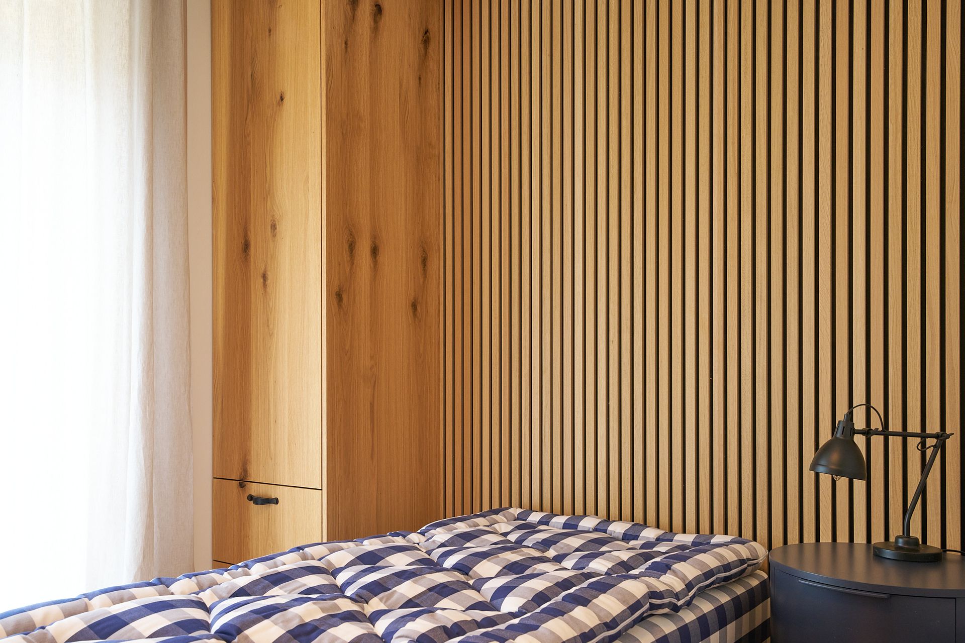 Ein Schlafzimmer mit Bett, Nachttisch, Lampe und Holzwänden.