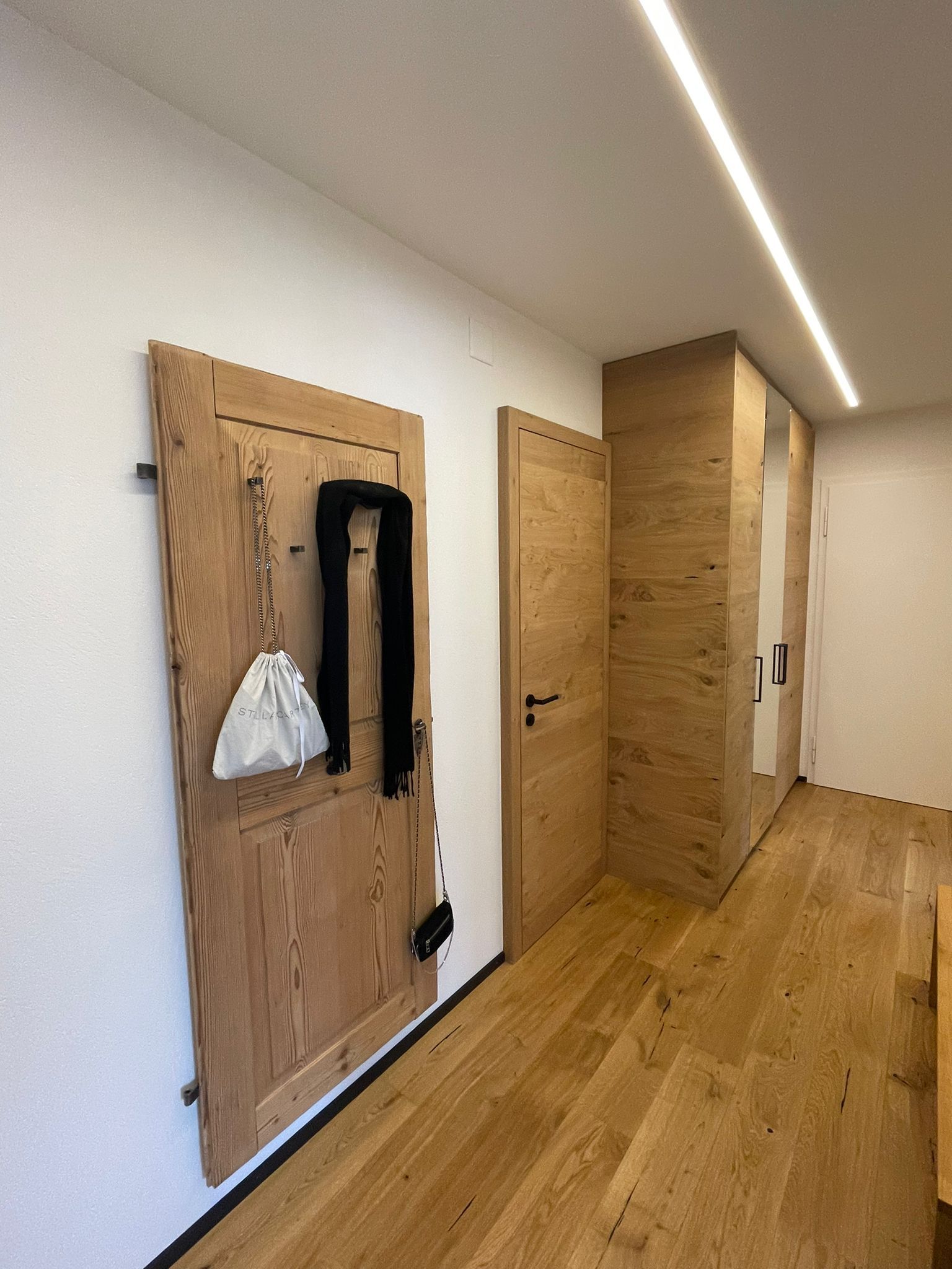 ein Flur mit Holzböden und einer an der Wand hängenden Holztür.