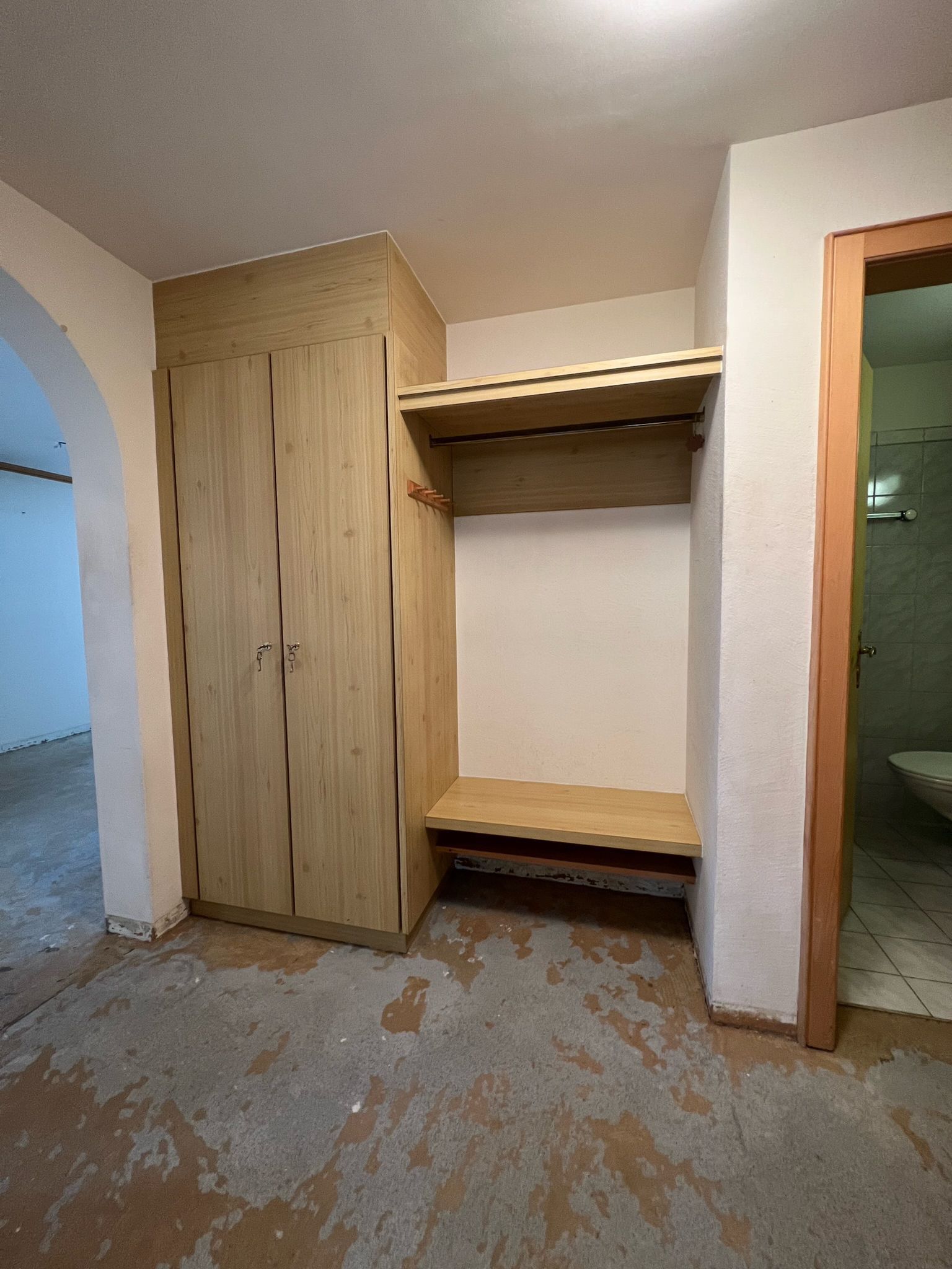 Ein Raum mit einem Schrank und einer Bank darin.