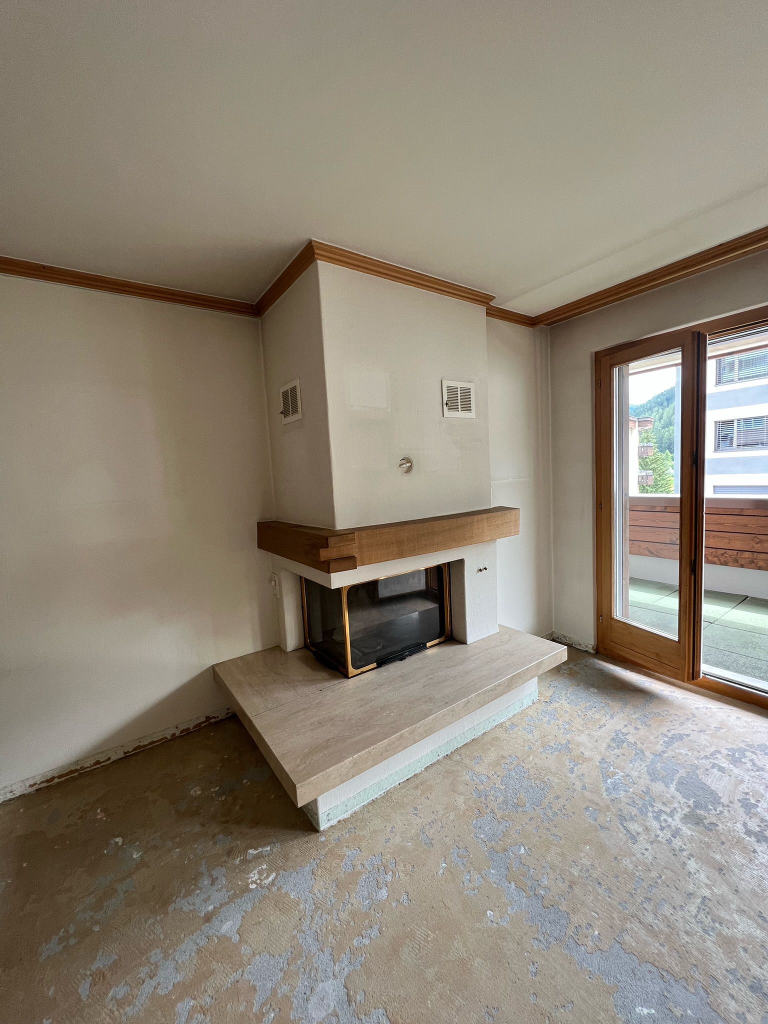 Ein leeres Wohnzimmer mit Kamin und Glasschiebetüren.