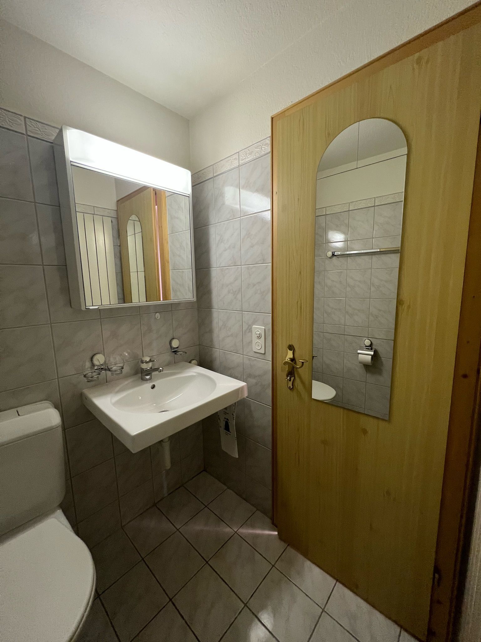 Ein Badezimmer mit Toilette, Waschbecken und Spiegel