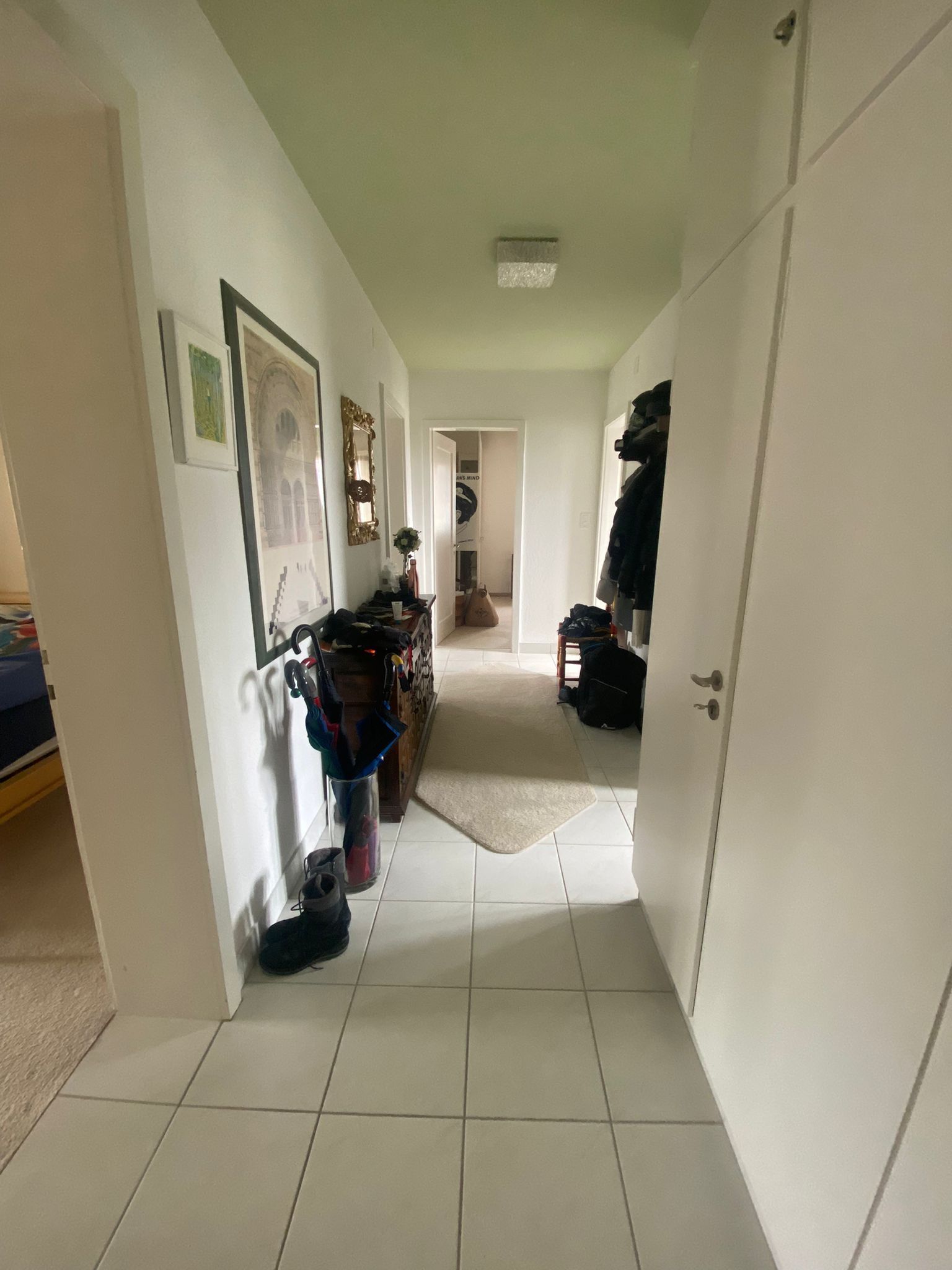 Ein langer Flur mit weißen Fliesenböden und weißen Wänden