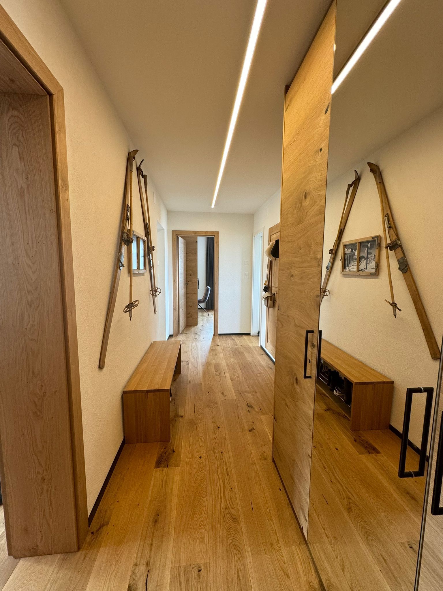 Ein Flur mit Holzboden und an der Wand hängenden Skiern