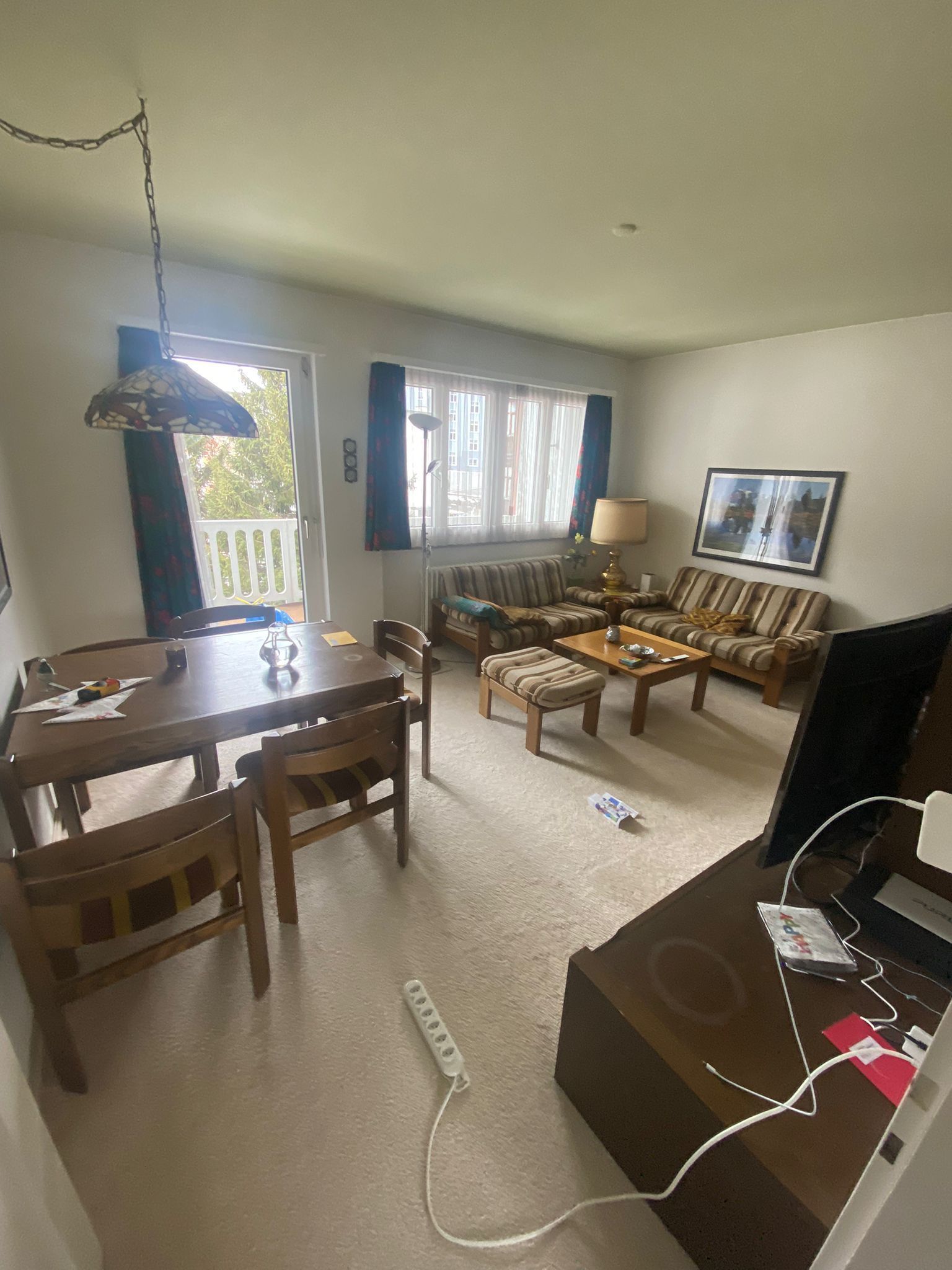 Ein Wohnzimmer mit Tisch, Stühlen, Couch und Fernseher.