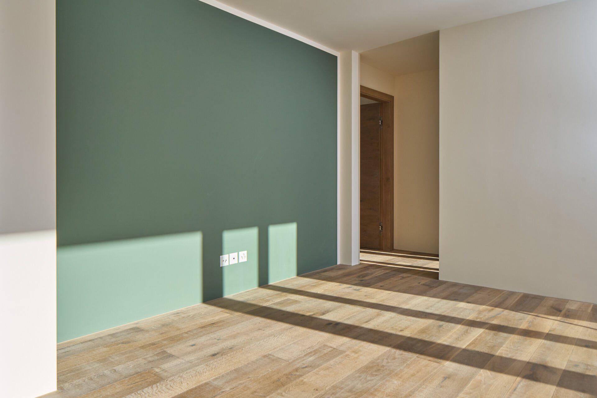 Ein leerer Raum mit einer grünen Wand und Holzboden.