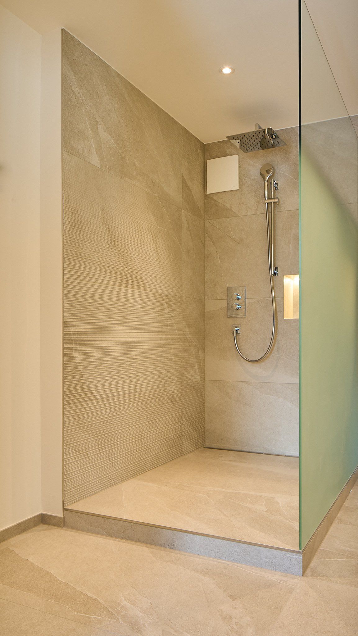 Ein Badezimmer mit ebenerdiger Dusche und Glaswand.