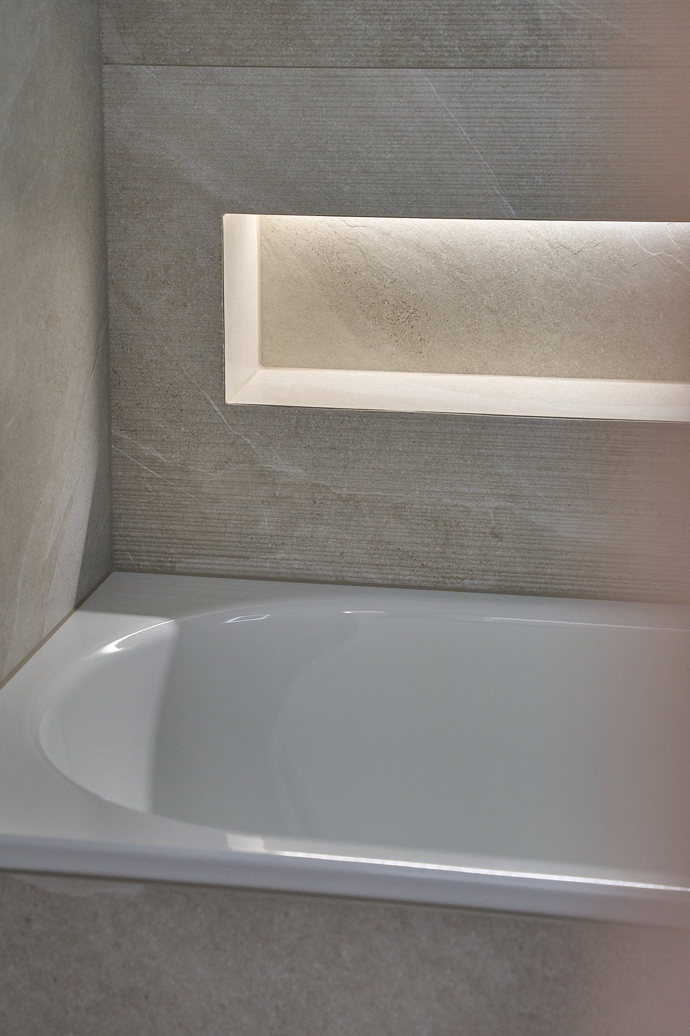 Eine Badewanne in einem Badezimmer mit einem Regal darüber.