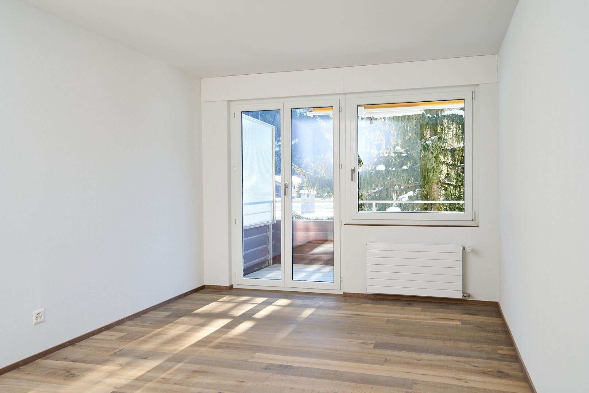 Ein leerer Raum mit einer Glasschiebetür und einem Fenster