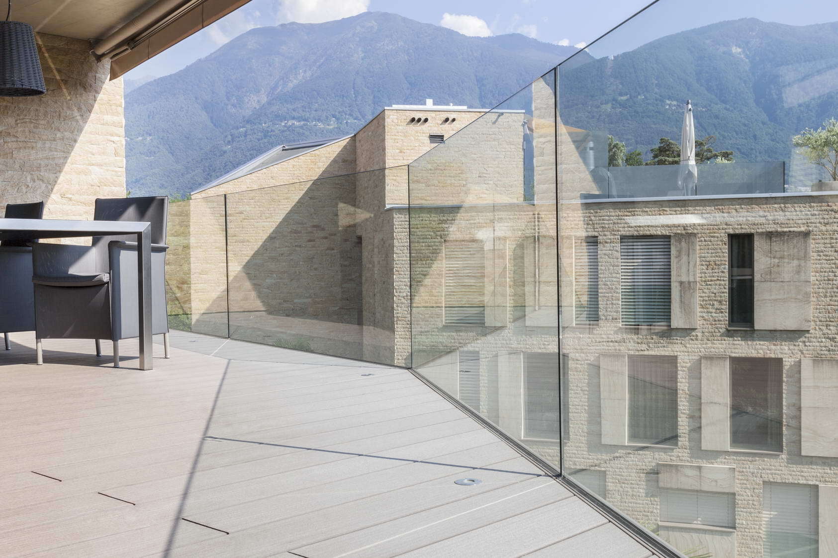 ein Balkon mit Glasgeländer und Bergen im Hintergrund