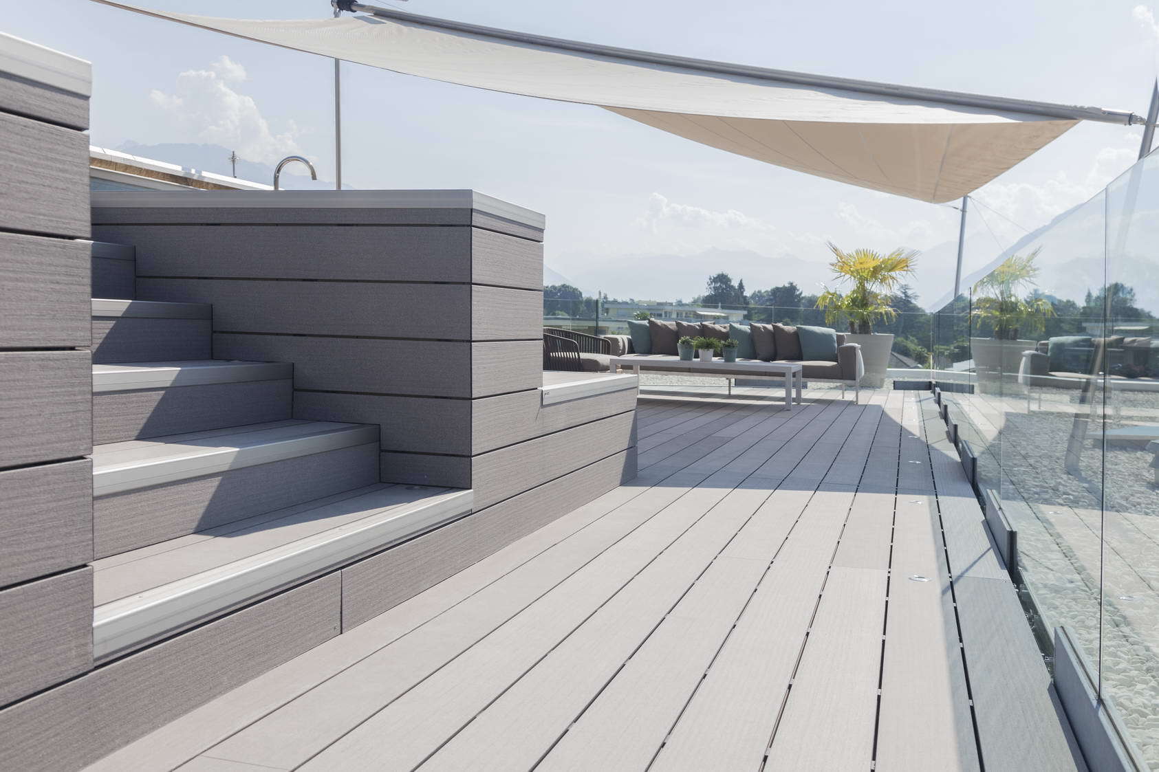 eine Holzterrasse mit Treppen und einem Glasgeländer