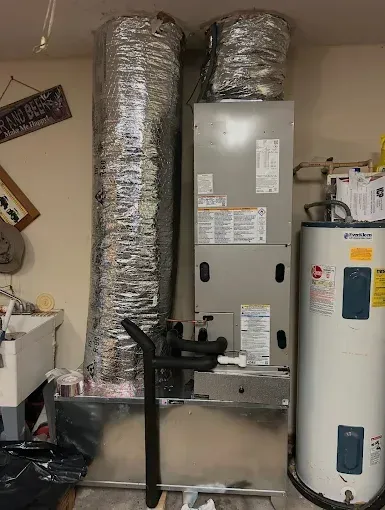 Utility room with furnace, water heater, and insulated ductwork against a wall.