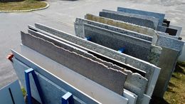 Several large stone slabs displayed upright in an outdoor lot on blue metal racks.