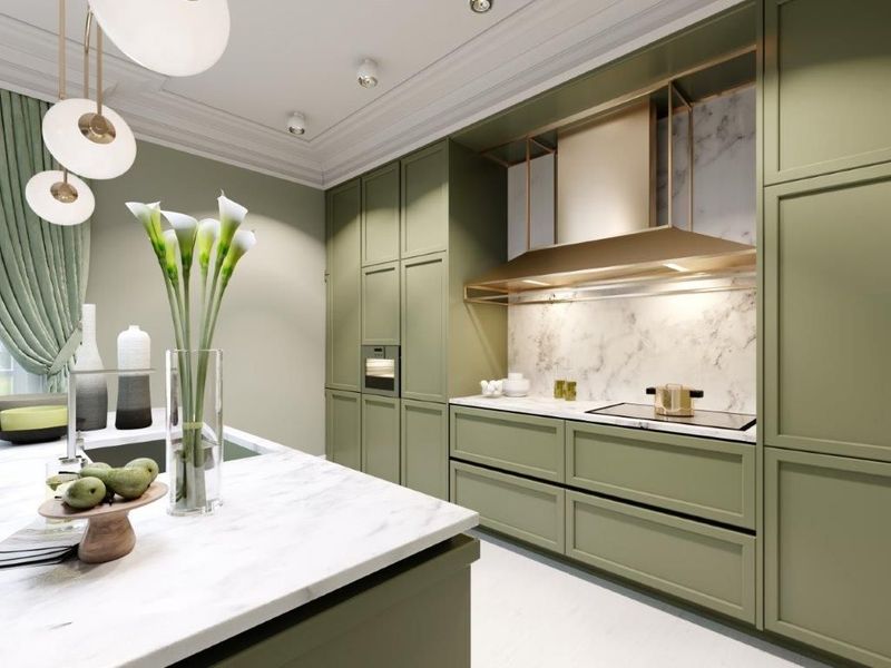 Modern green kitchen with white marble island, pendant lights, and copper range hood