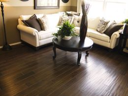 Bright living room with two white sofas, a round wooden coffee table, and dark hardwood floors