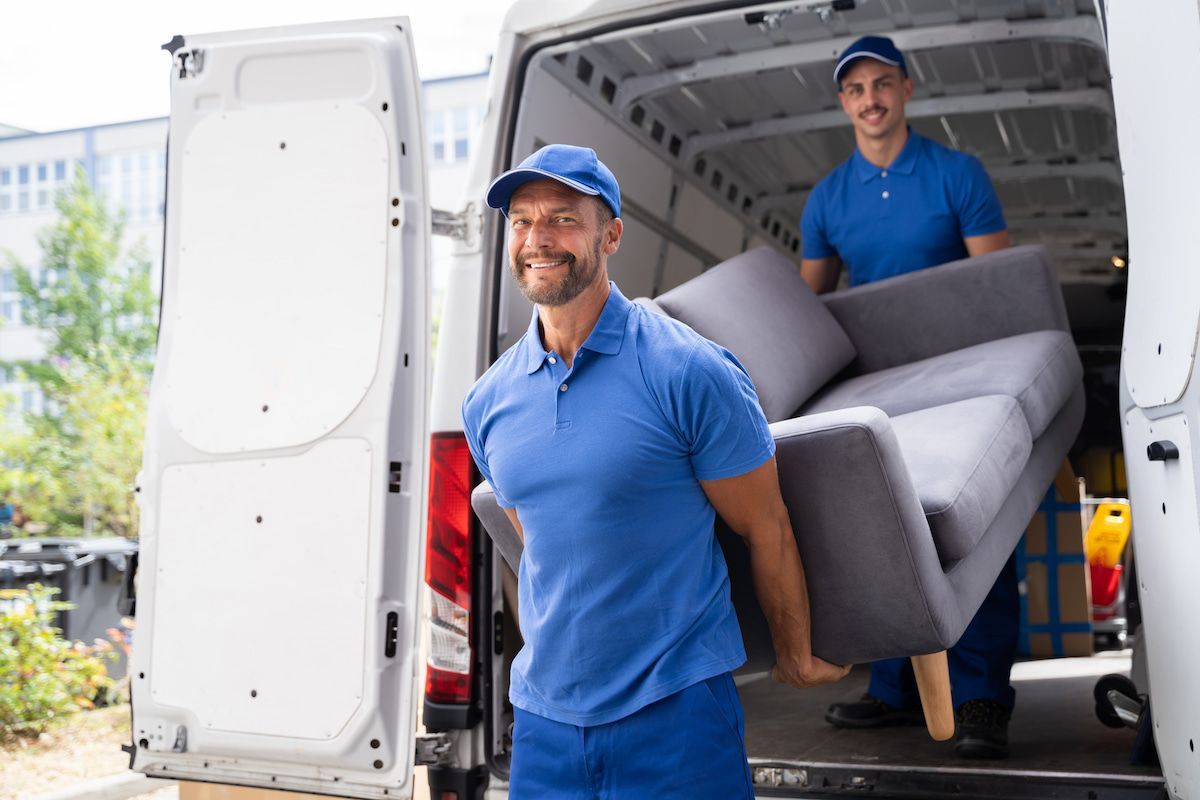 Two Men Are Carrying a Couch out Of a Van — Ocean Grove Removals In Bendigo, VIC